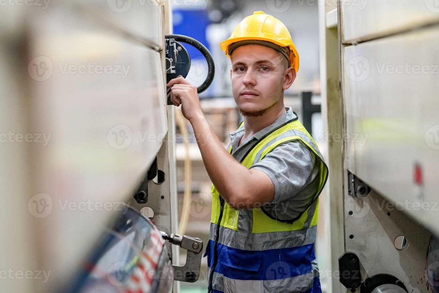 A man in a hard hat and safety vest is standing in a factory photo
