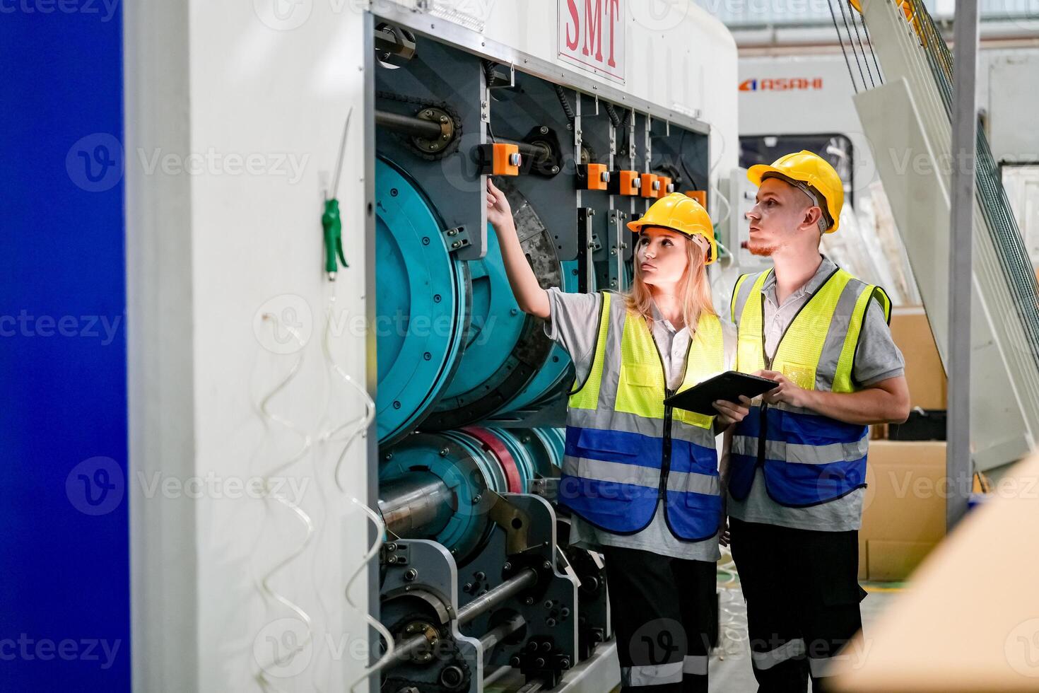 Two people in safety vests looking at a machine photo