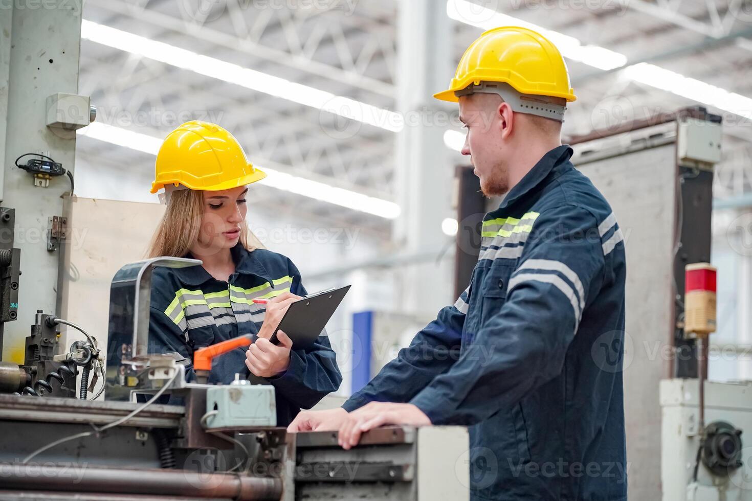 Two people in hard hats working on a machine photo
