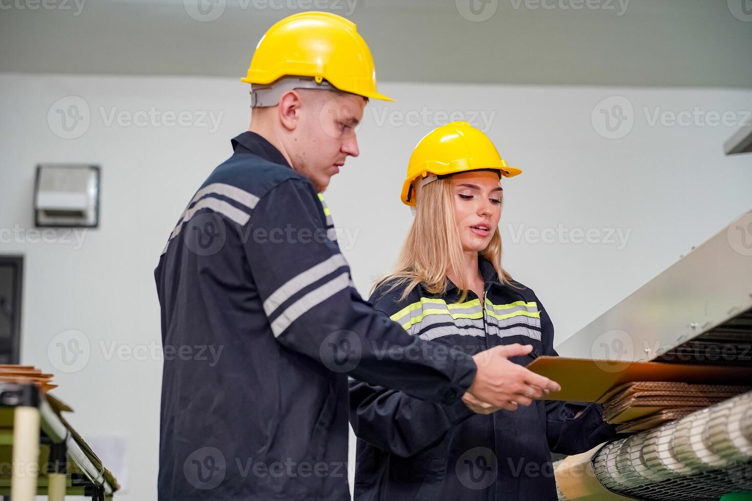 Two people in hard hats standing in front of a machine photo
