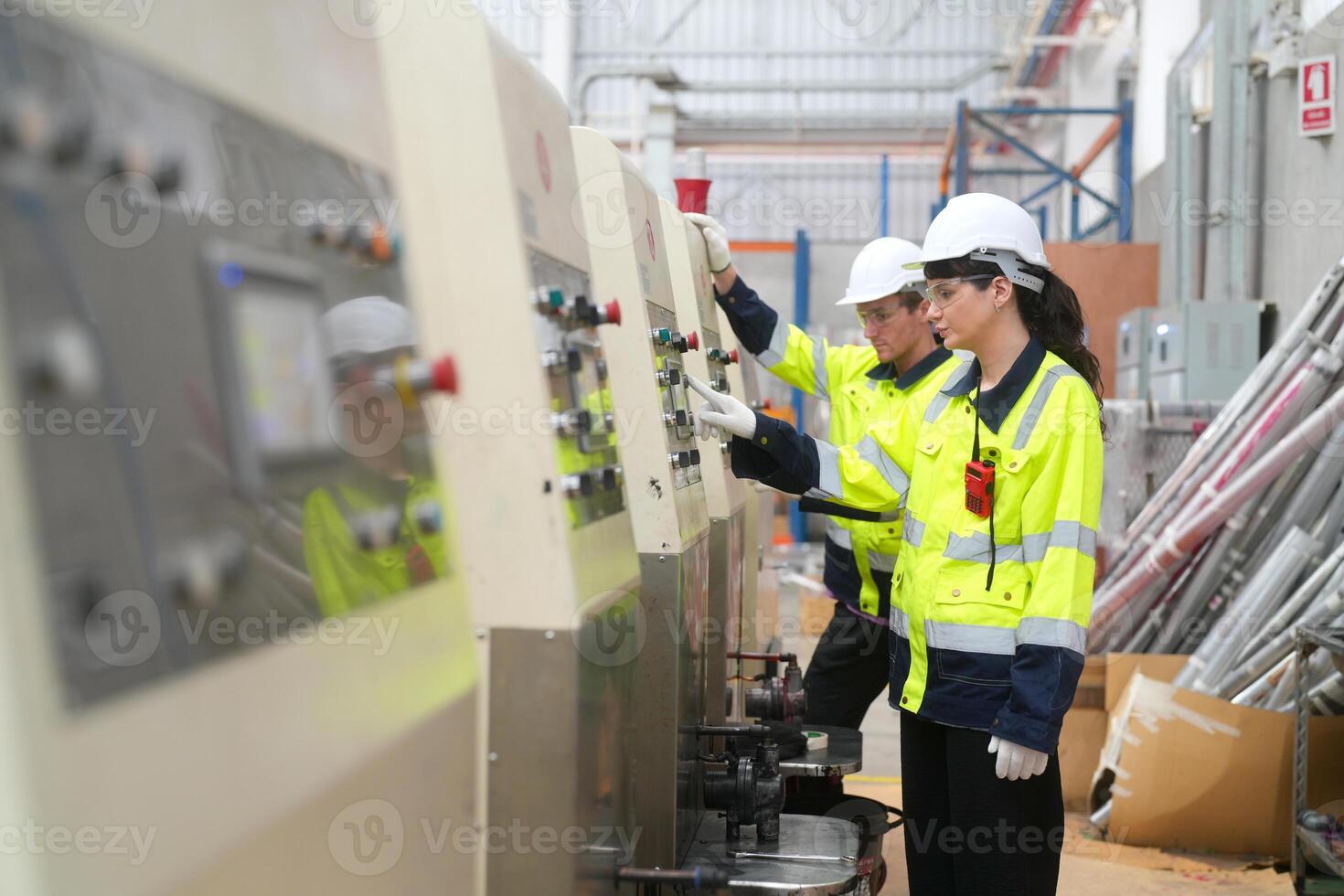 Two workers in safety gear working on a machine photo