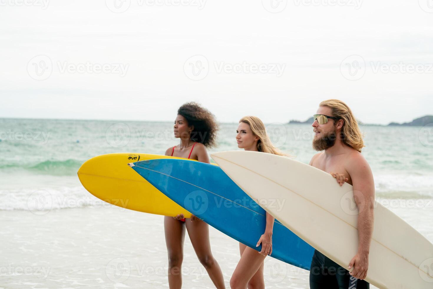 Three people walking on the beach with surfboards photo