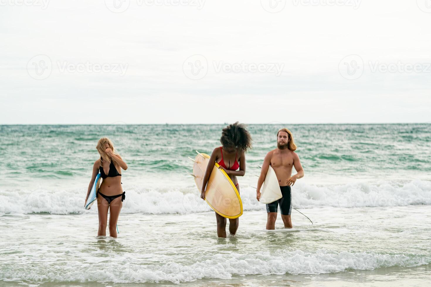 Three people standing in the ocean with surfboards photo