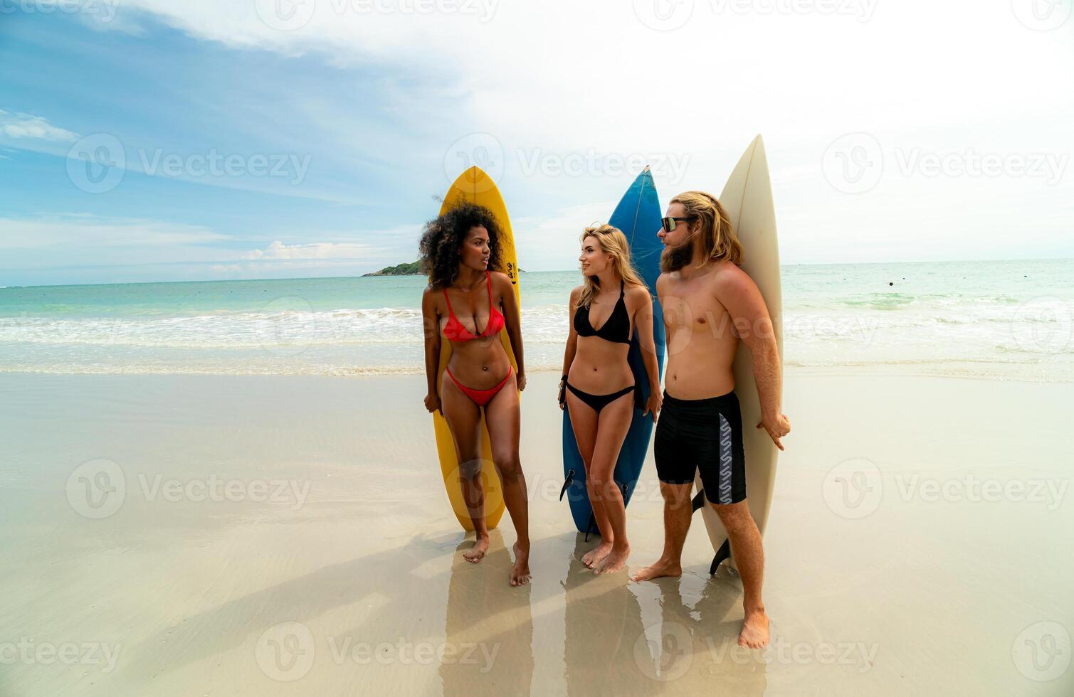 Three people standing on the beach with surfboards photo