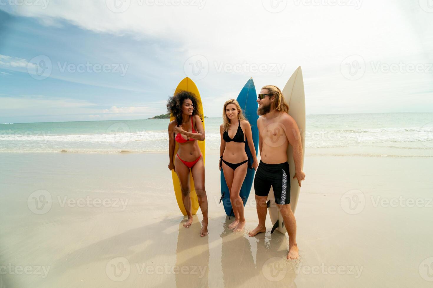 Three people standing on the beach with surfboards photo