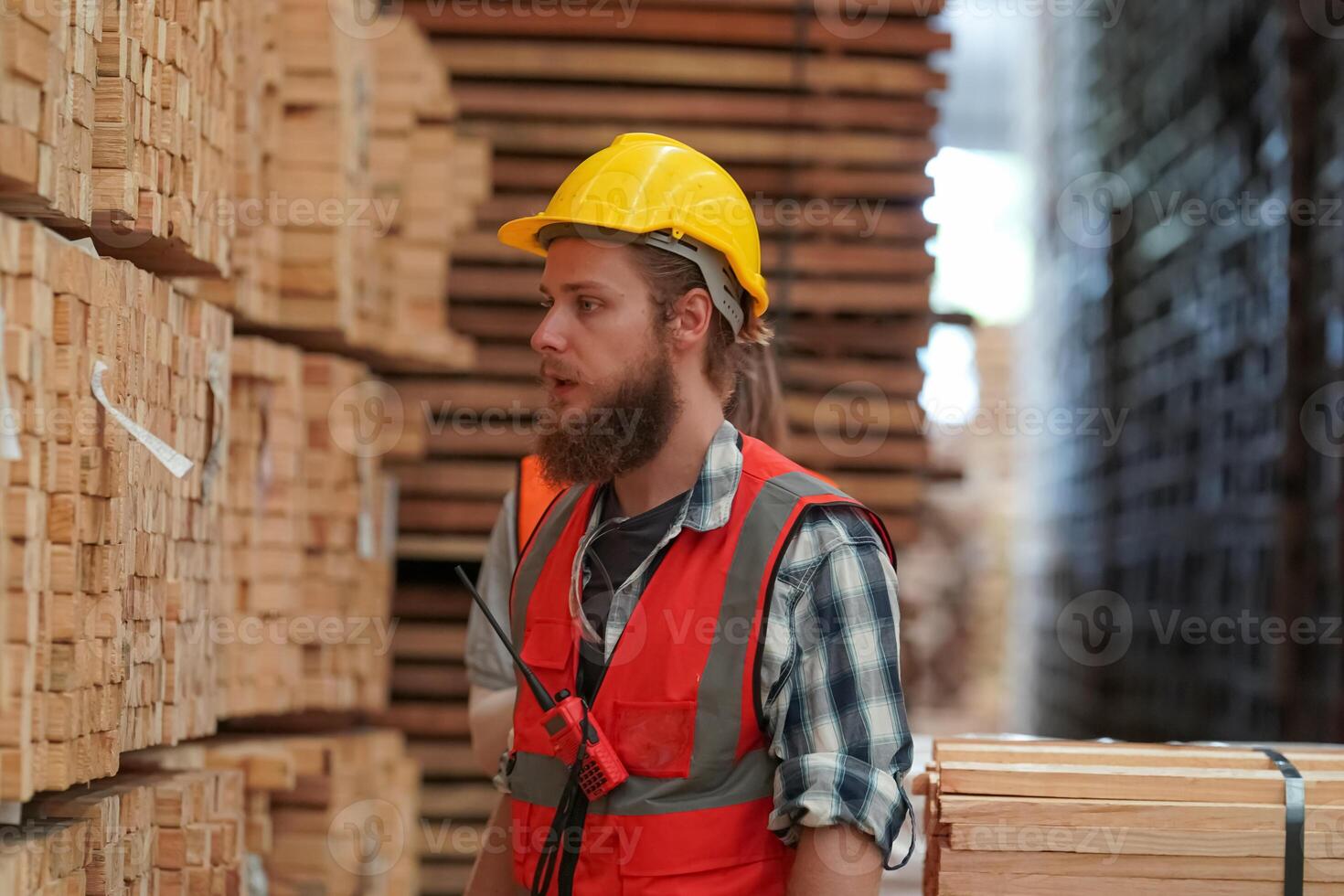 A man in an orange vest and hard hat standing in a warehouse photo