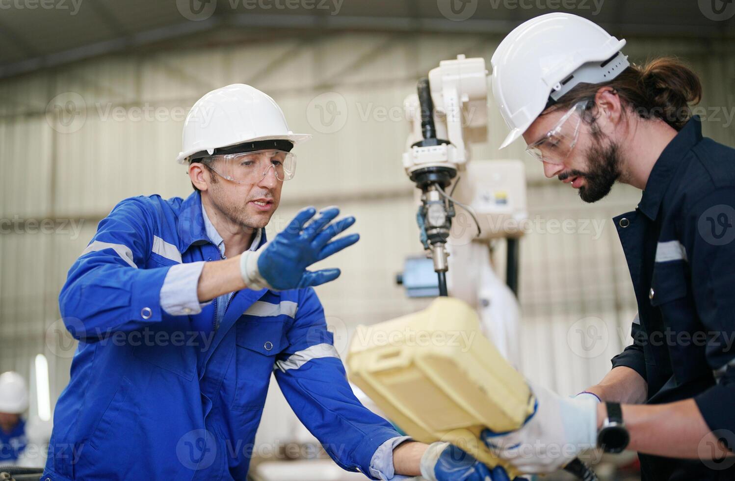 Two men in blue overalls working on a machine photo