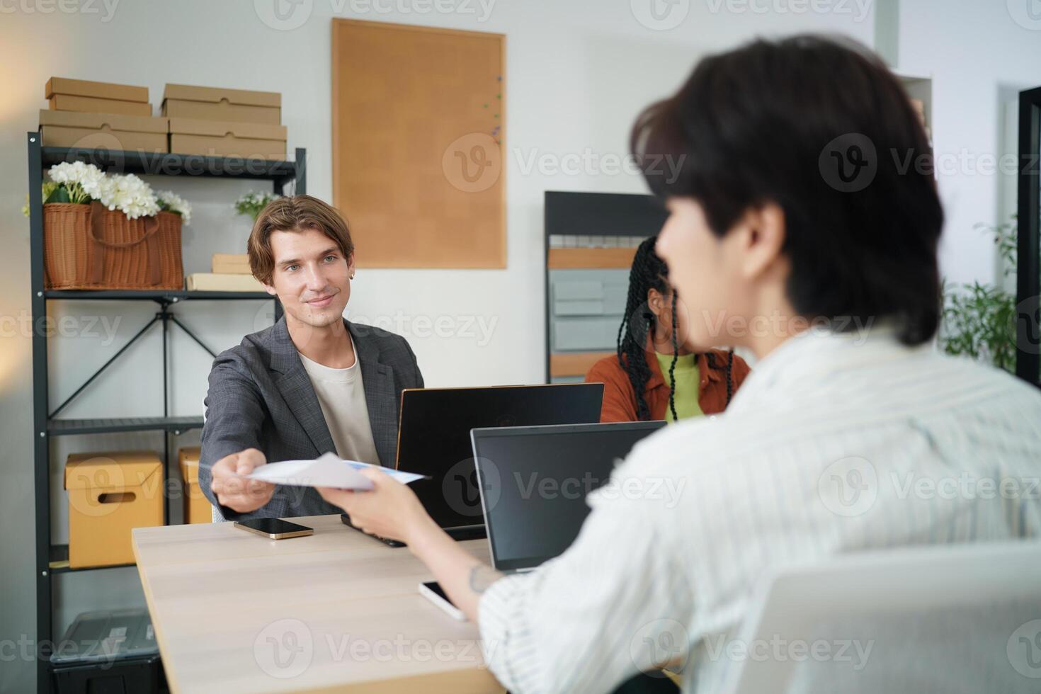 A man is handing a document to a woman at a desk photo