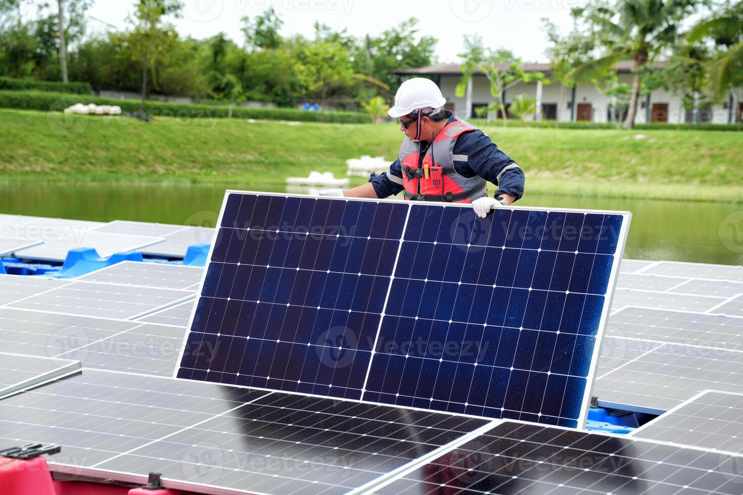 A man in a hard hat and safety vest is working on a solar panel photo