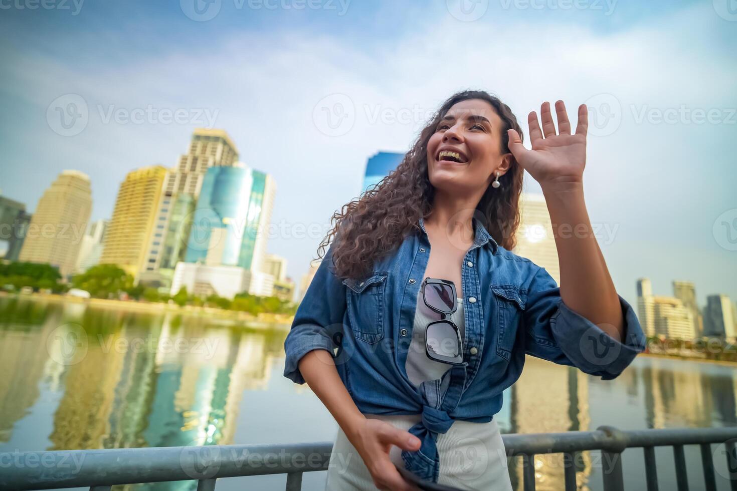 A woman waving in front of the city skyline photo