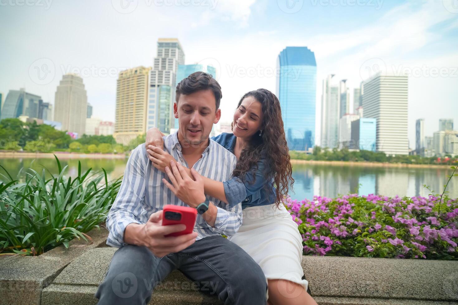A man and woman are sitting on a bench in front of a city photo