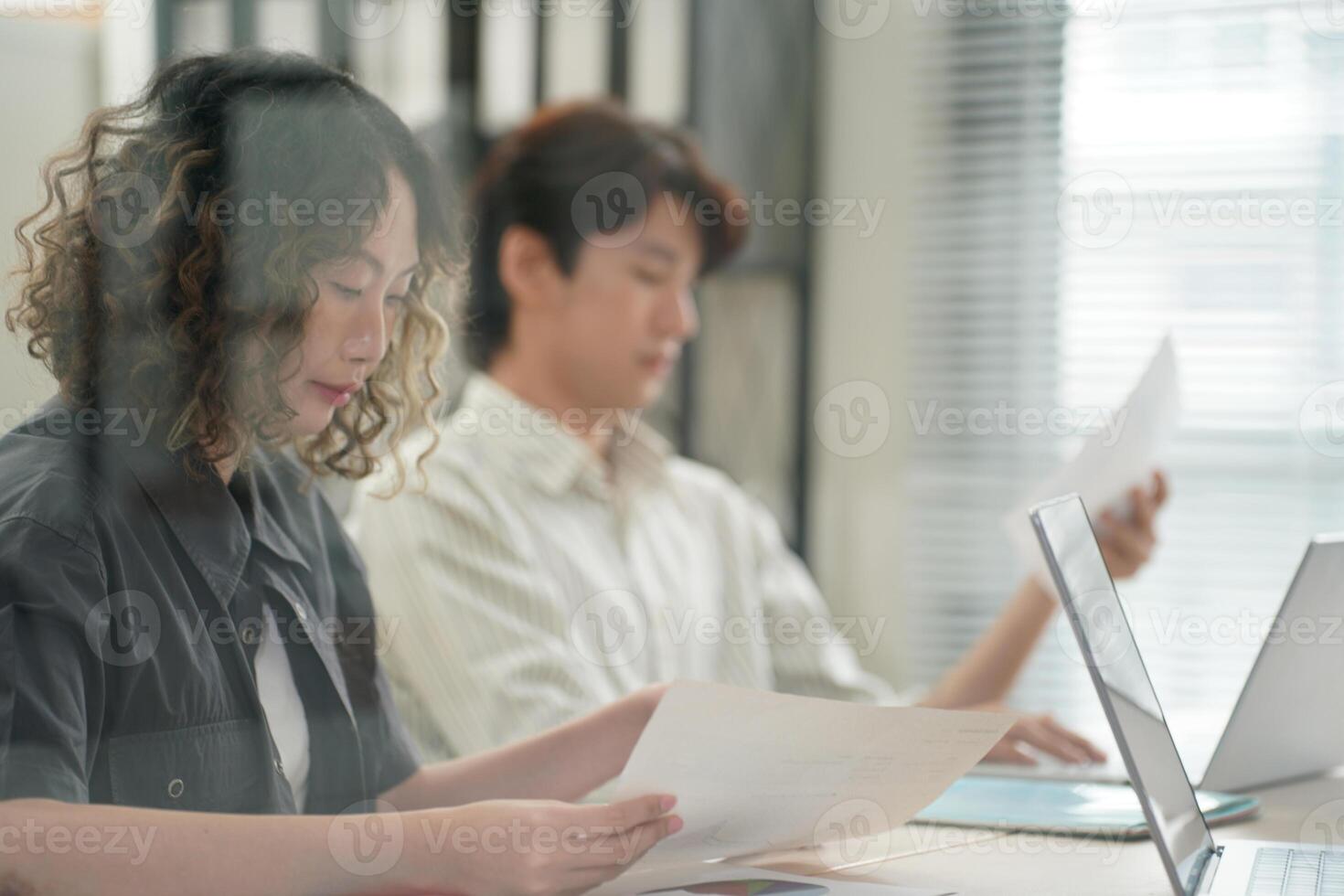 Two people sitting at a table with laptops photo