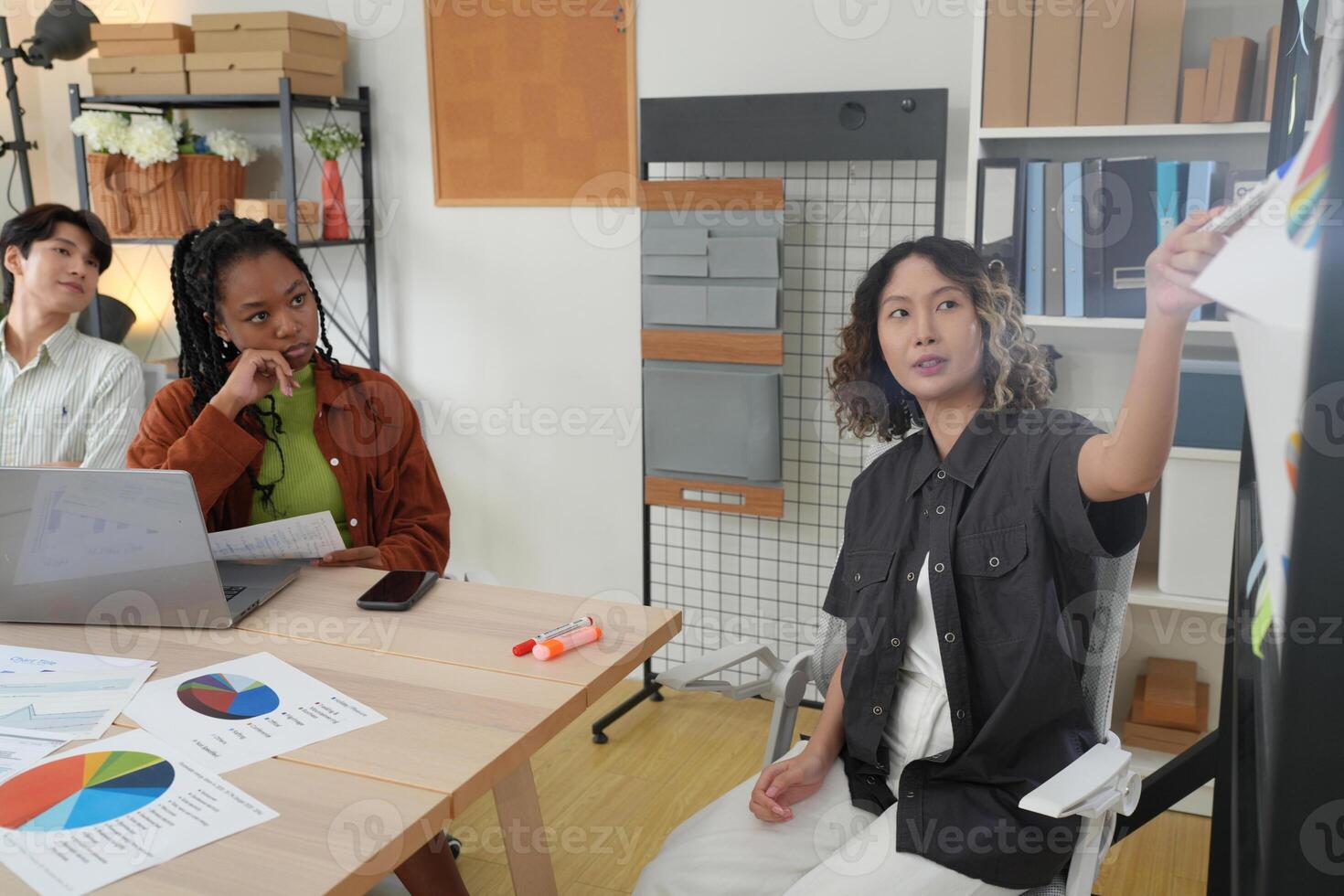 Three people sitting at a table with a laptop and papers photo