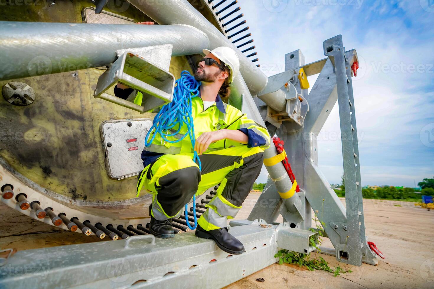 A man in a safety vest is fixing a large metal object photo