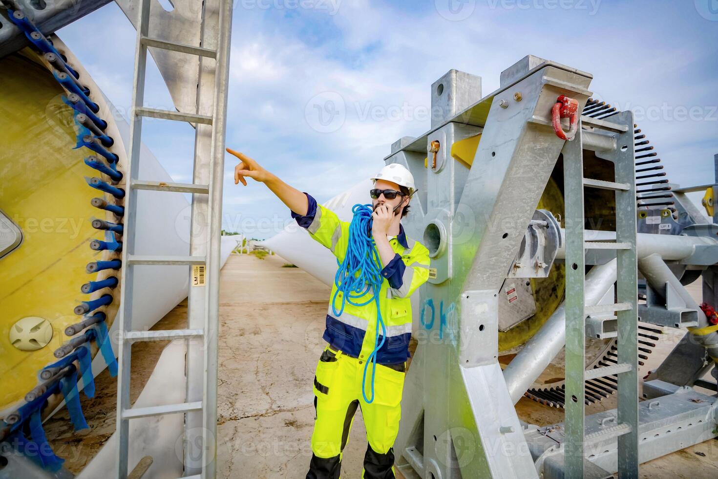 A worker in safety gear standing next to a wind turbine photo