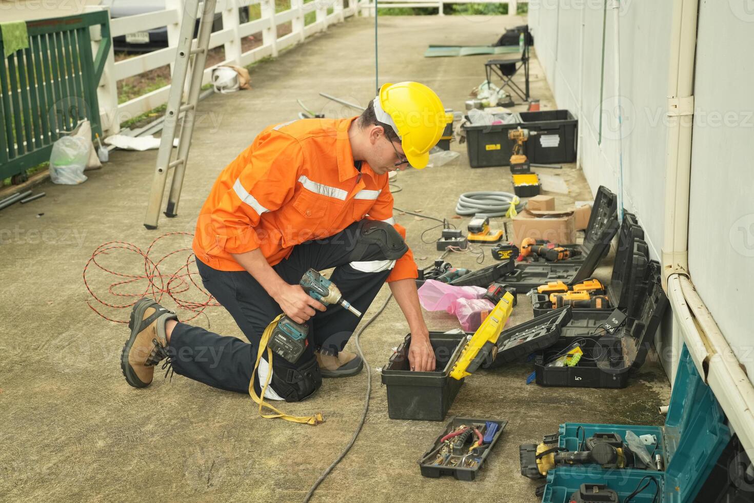 A man in an orange shirt and yellow helmet working on a tool photo