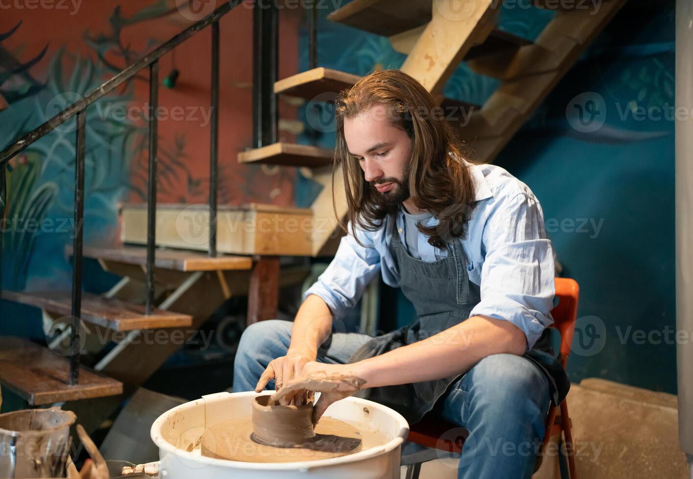 A man is making pottery on a pottery wheel photo