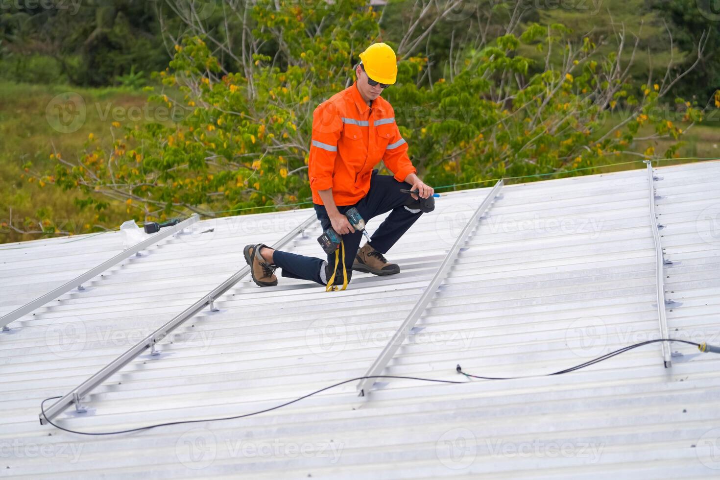 A man in an orange shirt and safety vest on the roof photo