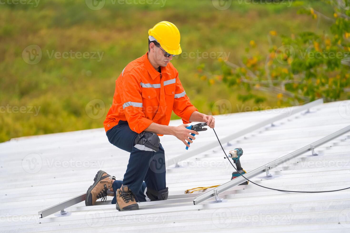 A man in an orange shirt and hard hat working on a roof photo