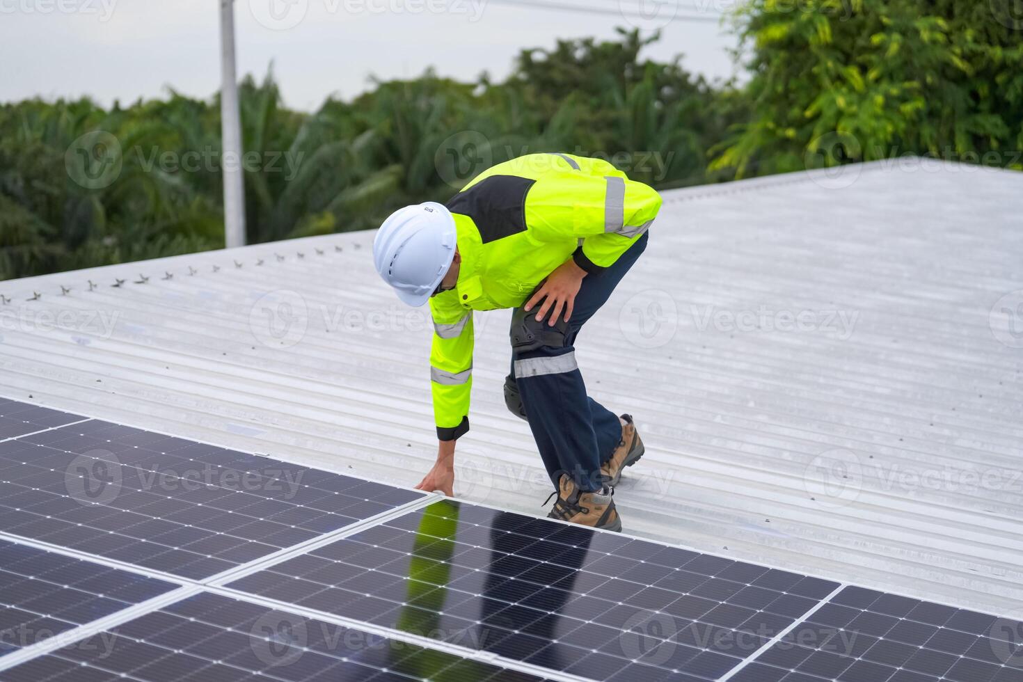A man in a safety vest and hard hat is working on a solar panel photo
