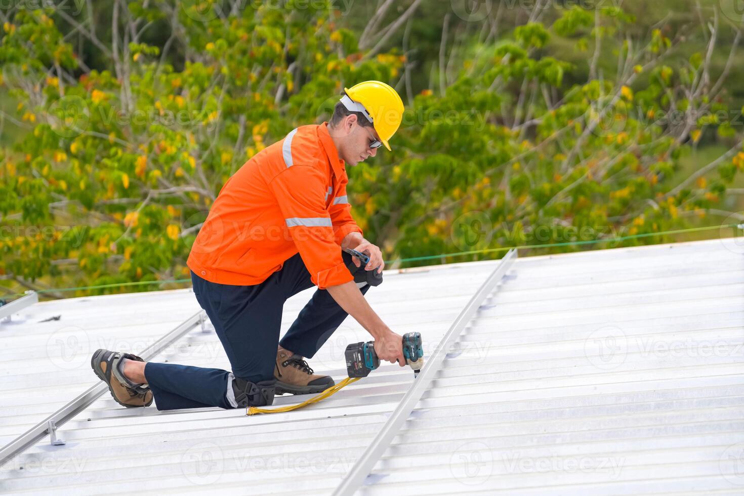 A man in an orange shirt and safety vest working on a roof photo