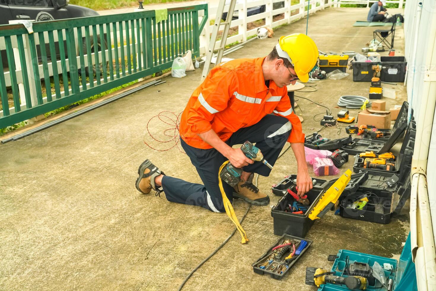 A man in an orange shirt and safety vest working on a power tool photo