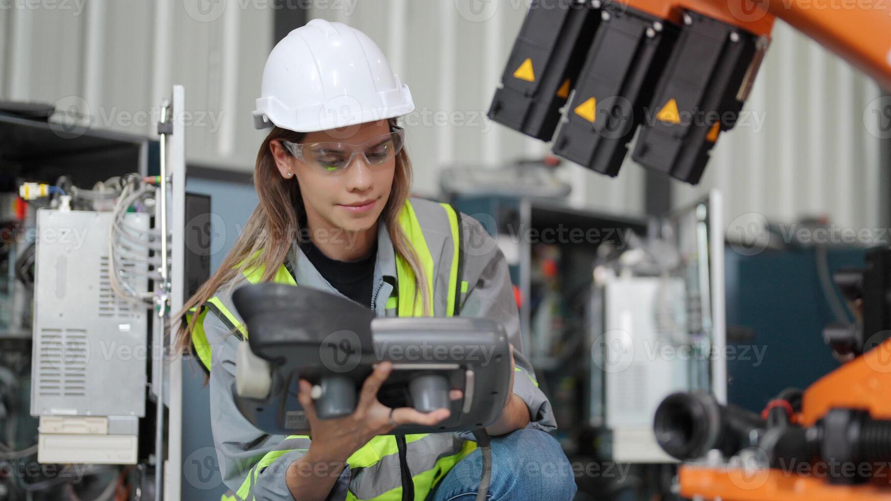 A woman in a hard hat and safety vest holding a remote control photo