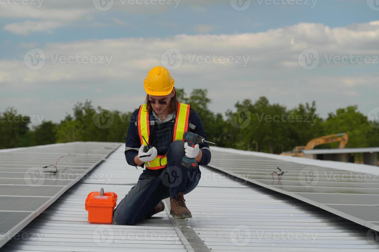 A man in a hard hat and safety vest working on a solar panel photo