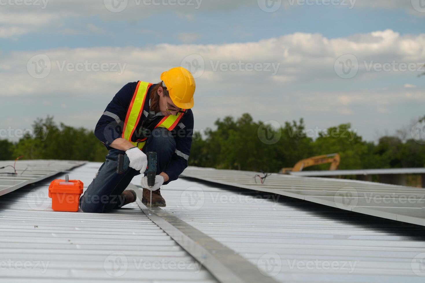 A man in a hard hat and safety vest working on a metal roof photo