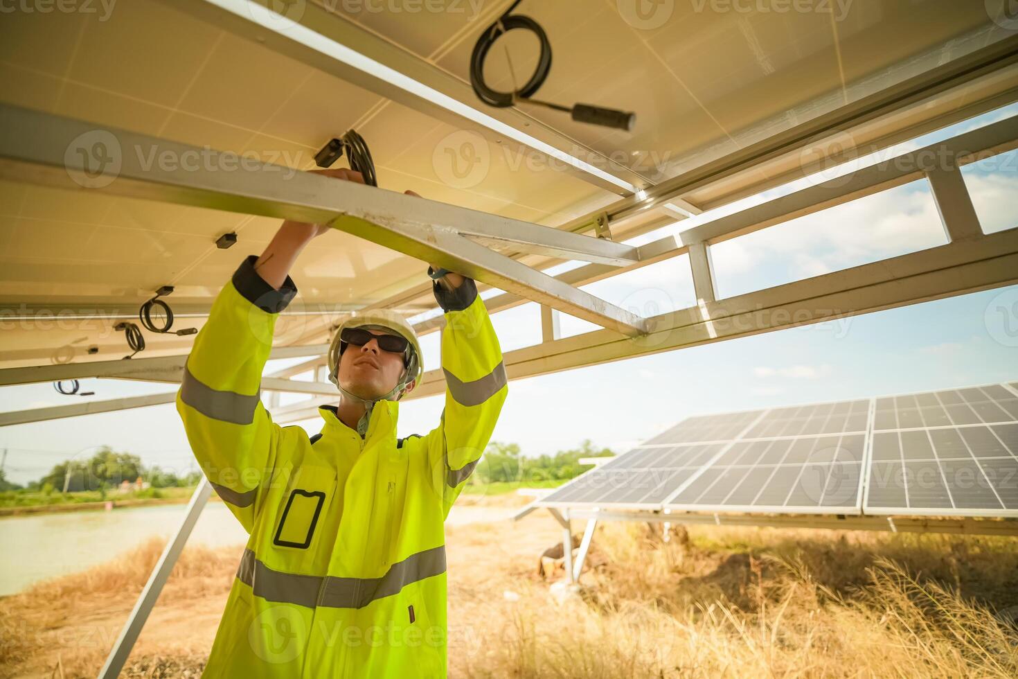 A man in yellow safety gear is fixing a solar panel photo