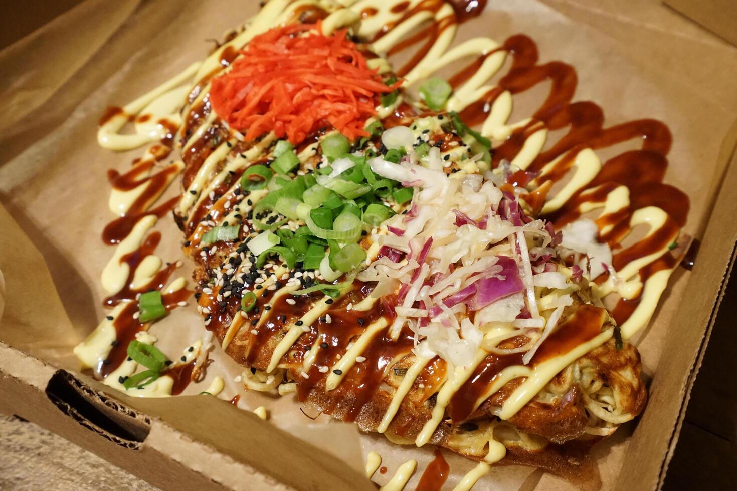 Close up Okonomiyaki, Japanese style savory pancake made with flour, eggs, shredded cabbage, meat and topped with a variety of condiments photo