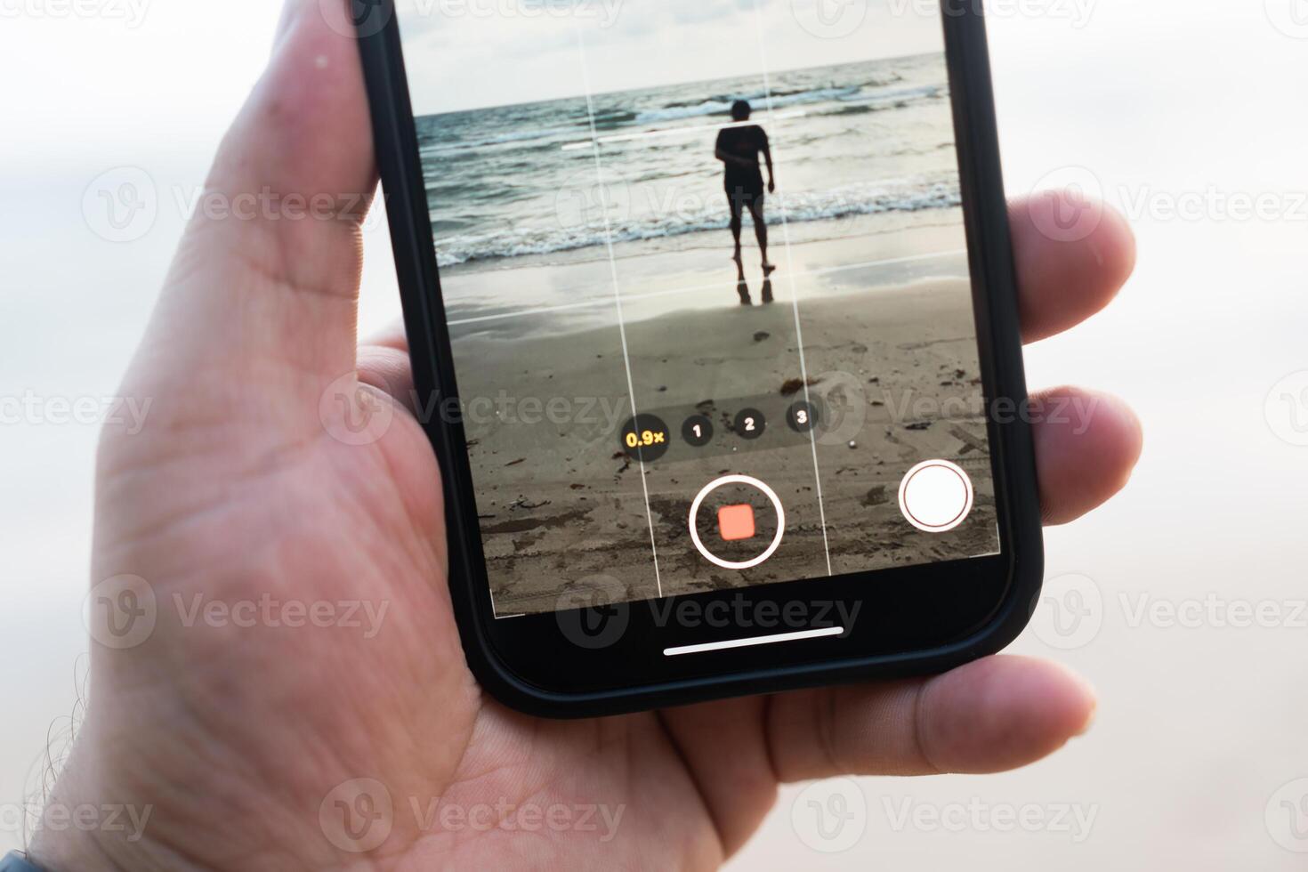 Shooting with phone. Shooting man walking at the beach photo