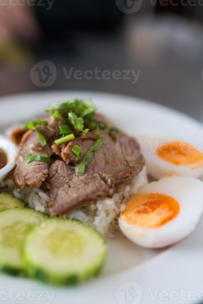Slice of stewed pork eaten with rice served with boiled egg and cucumber sprinkled with coriander. photo