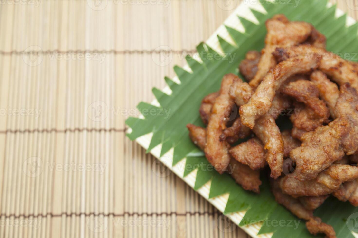 A plate of fried meat on a bamboo mat photo