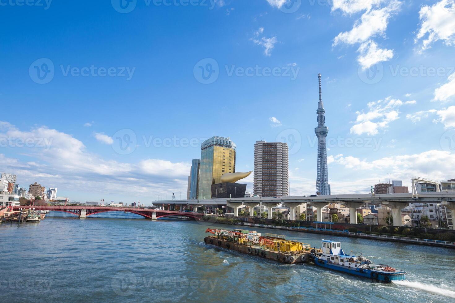 A boat traveling down a river with tall buildings in the background photo