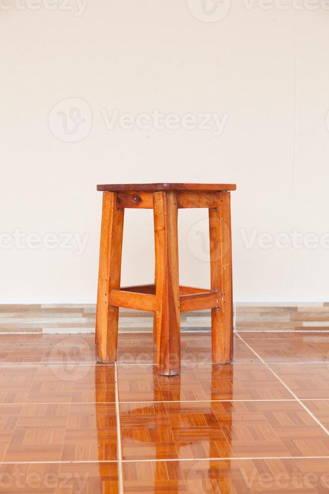 A wooden stool sitting on a tiled floor photo