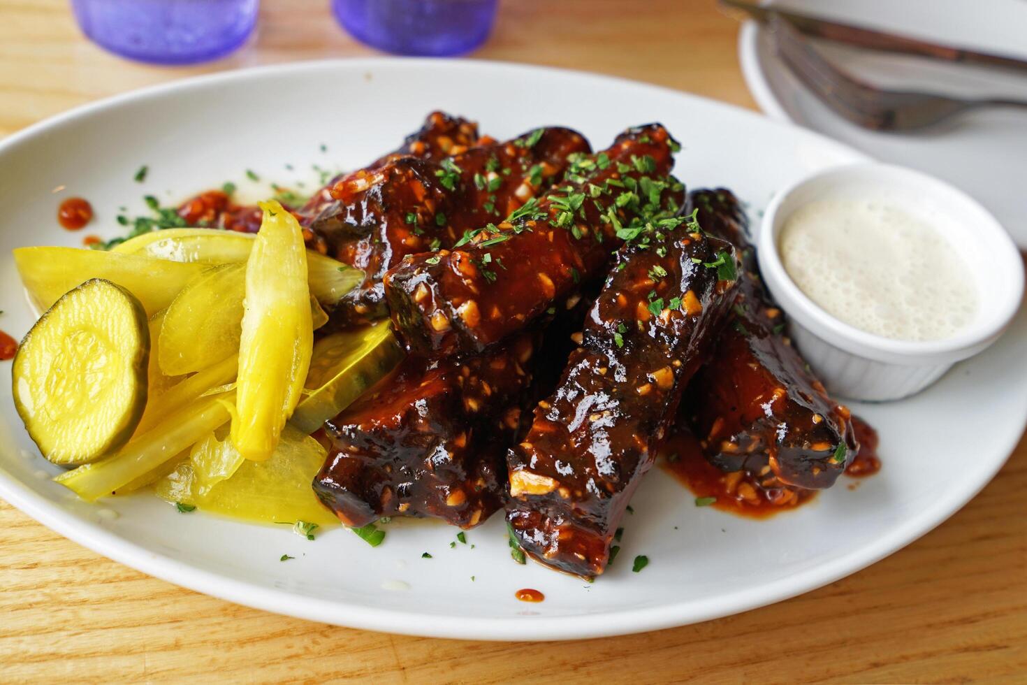 Close up barbecue pork cut ribs served with pickles and ranch sauce photo