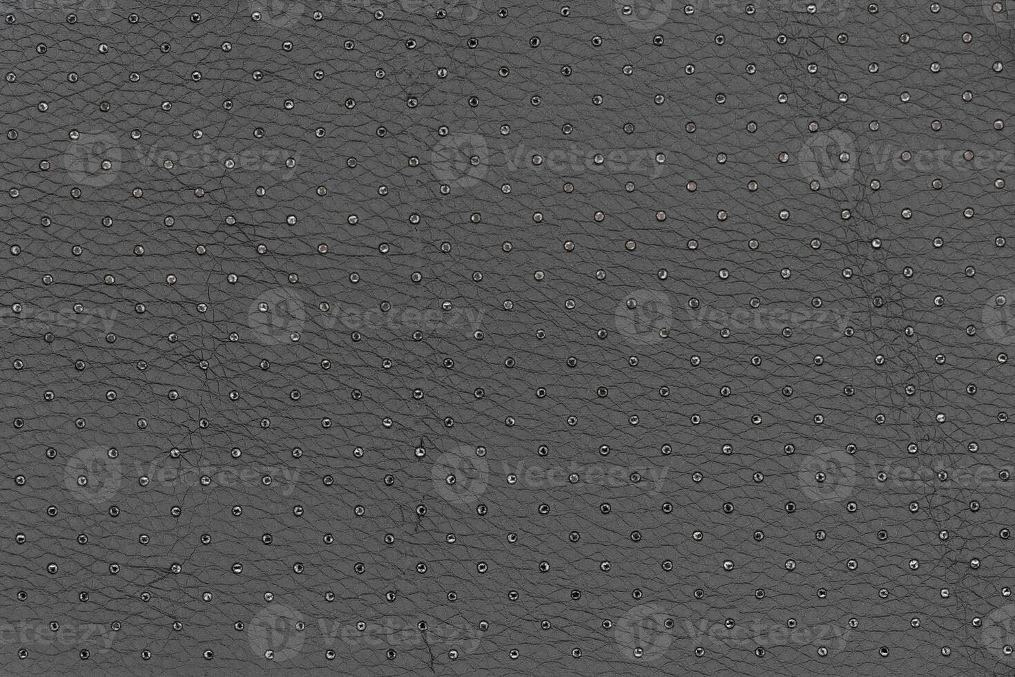 Abstract artificial leather in black with small dots and holes pattern for background. Tabletop view photo