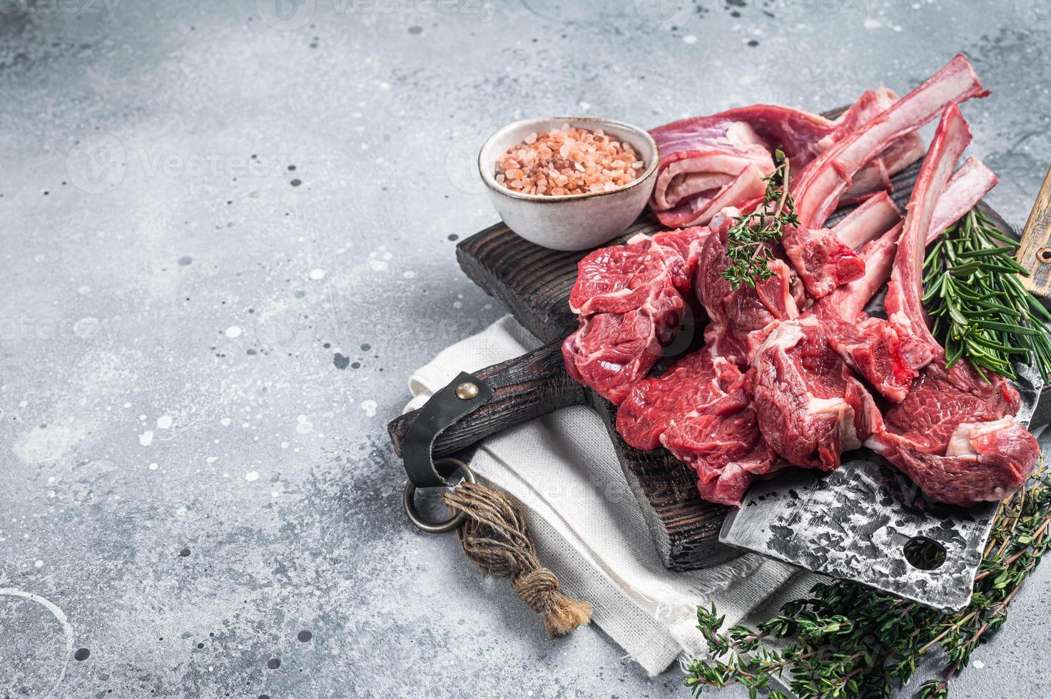 Butcher cutting board with butchered Raw Lamb chop steak or mutton cutlet. Gray background. Top view. Copy space photo