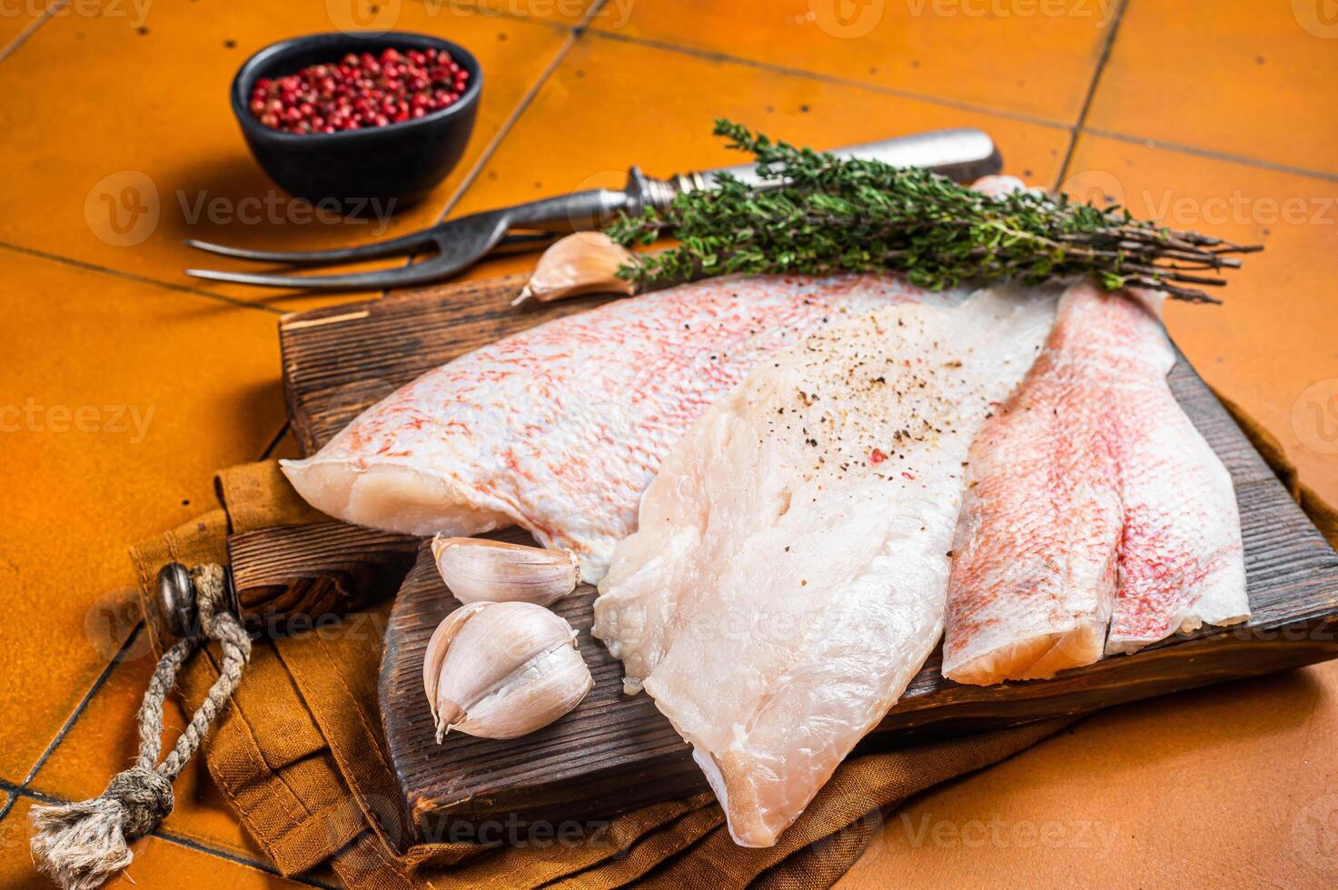 Uncooked ocean red perch fillet, redfish with herbs and spices. Orange background. Top view photo