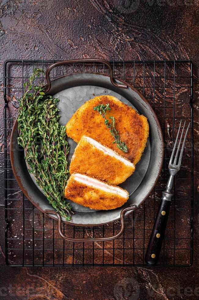 Cordon bleu chicken fillet cutlet with ham and cheese. Dark background. Top view photo