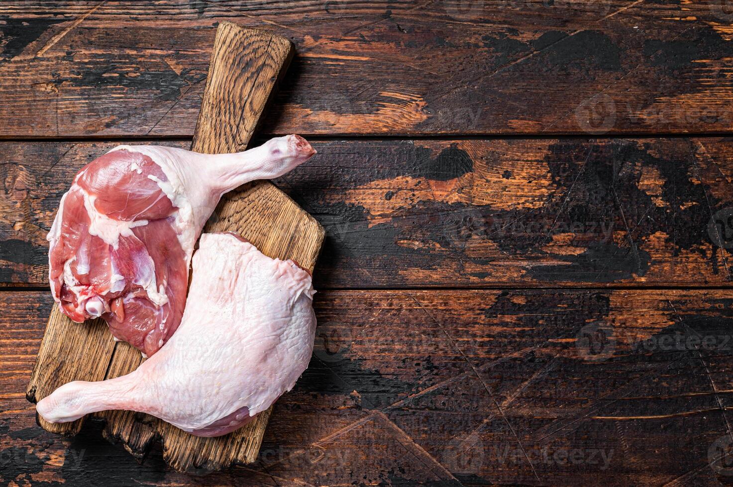 Uncooked Raw duck legs, Poultry meat on a wooden board. Wooden background. Top view. Copy space photo