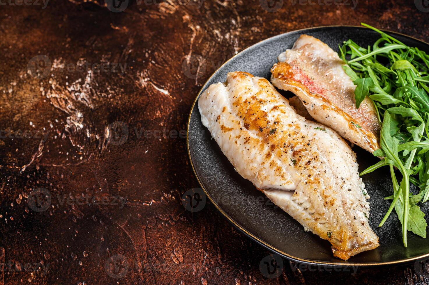 Roasted Snapper, sea red perch fillet on a plate with salad. Dark background. Top view. Copy space photo