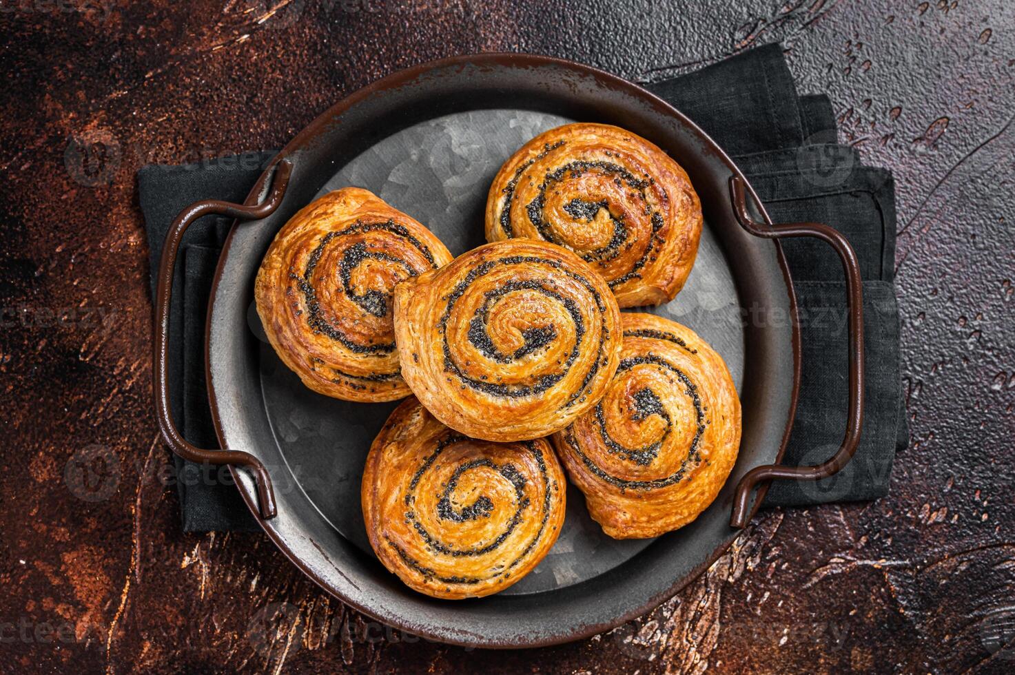 Sweet twisted Bun with poppy seeds and lavender. Dark background. Top view photo