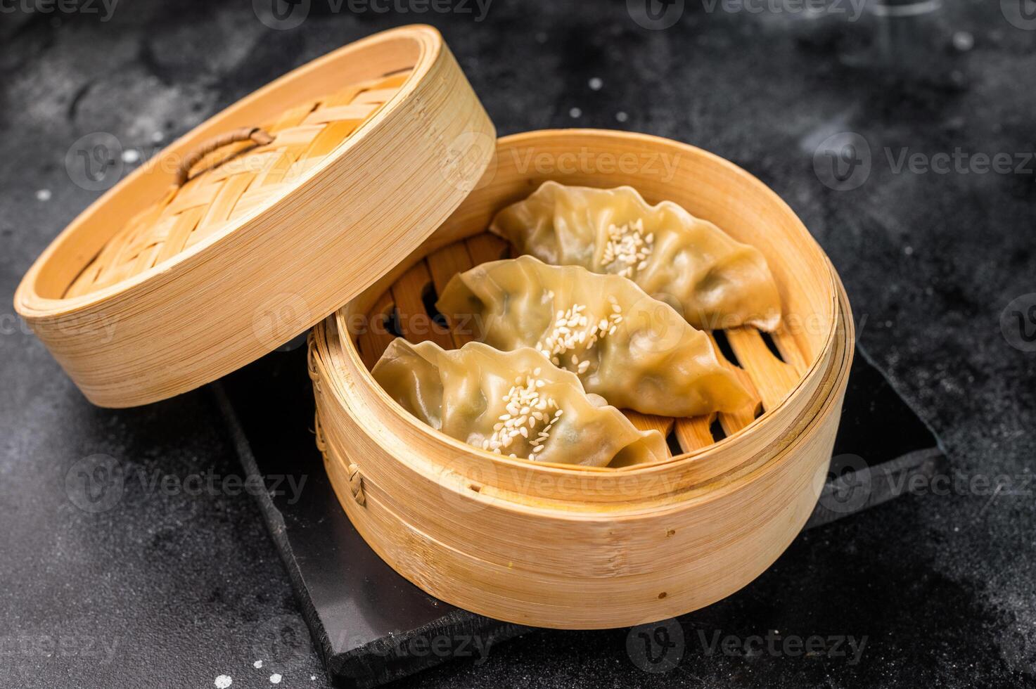 Steamed Korean Dumplings with pork meat and vegetables in bamboo steamer. black background. top view photo