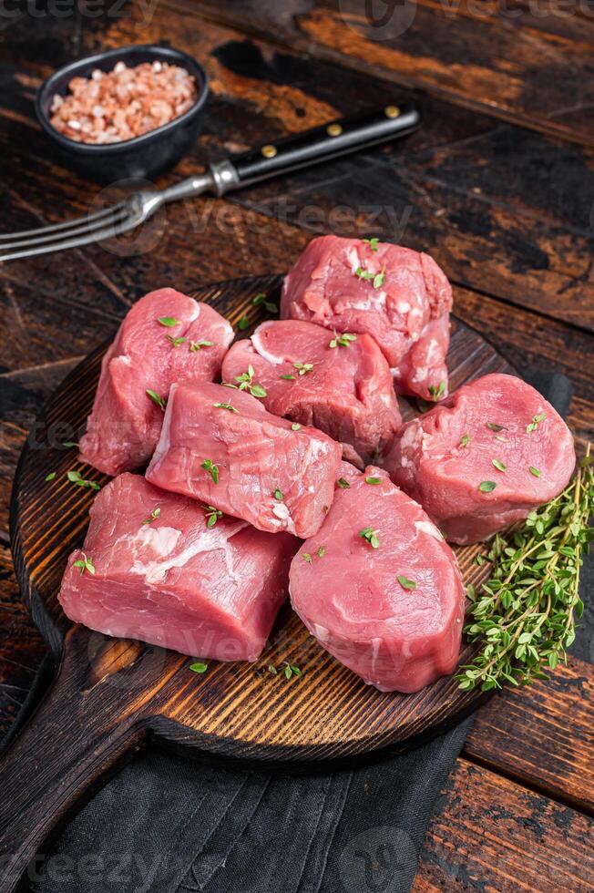 Raw pork sliced tenderloin fillet meat for medallions steaks on a wooden cutting board. Wooden background. Top view photo