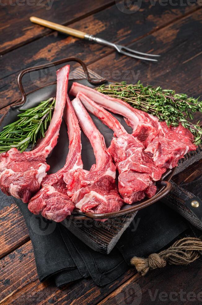 Fresh Raw Lamb chop steak in steel tray with herbs. Wooden background. Top view photo
