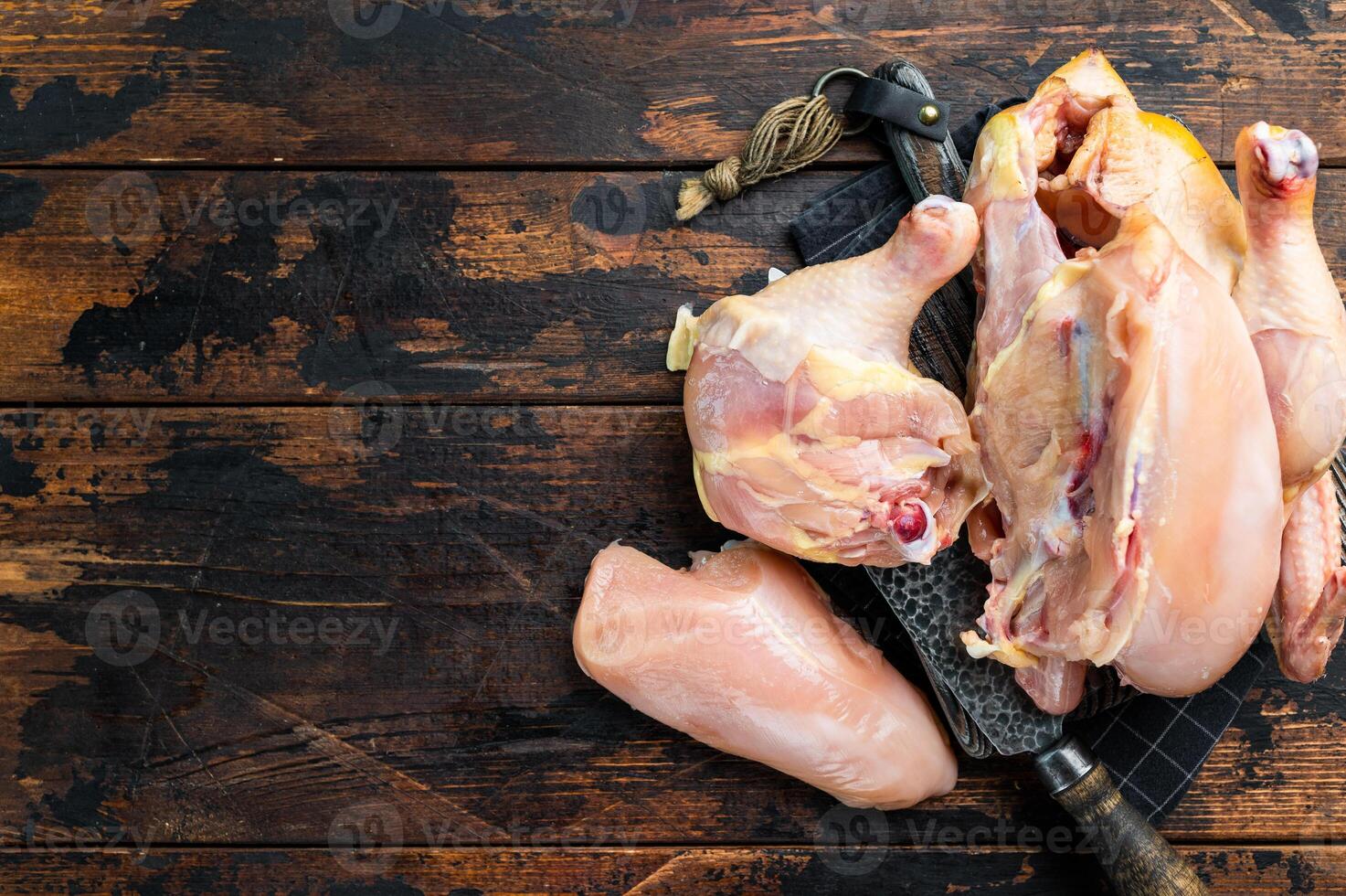 Raw chicken pieces on a wooden table, ready for cooking photo