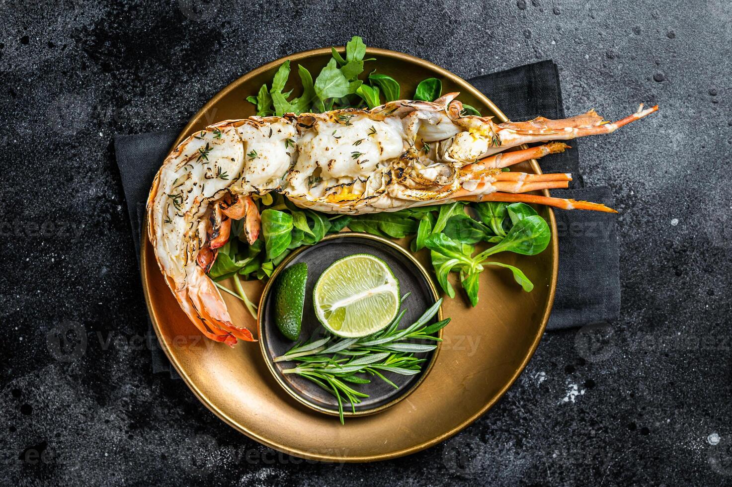 Grilled Spiny lobster with salad on a plate. Black background. Top view photo