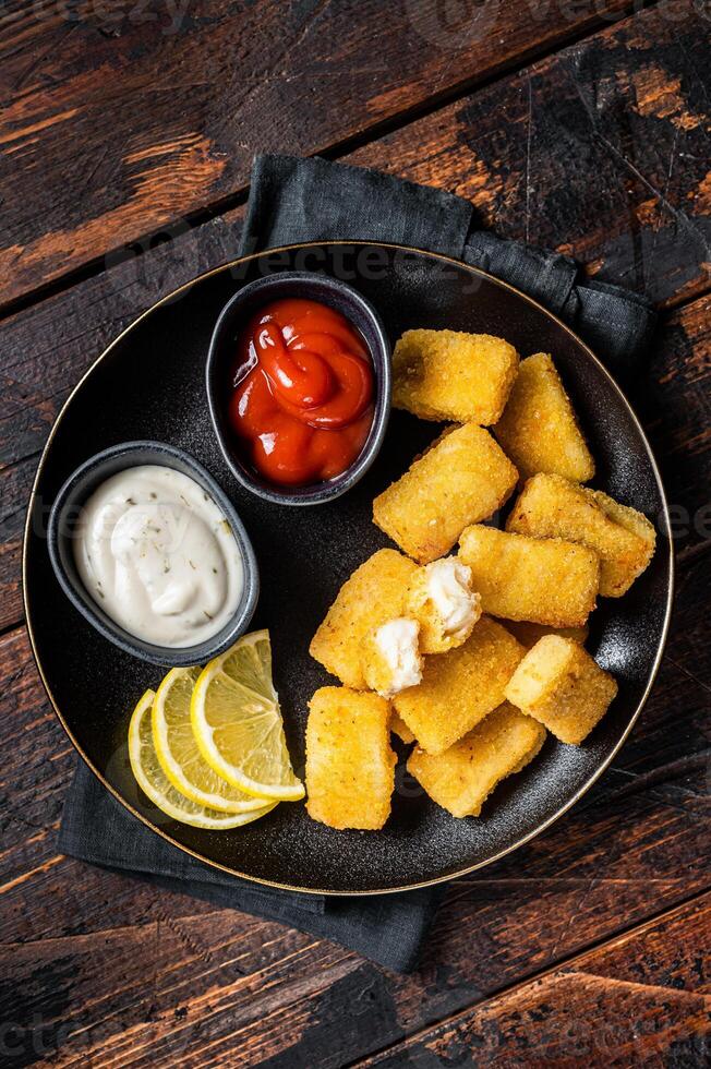 Fried Fish Sticks Fingers with sauce in a plate. Wooden background. Top view photo